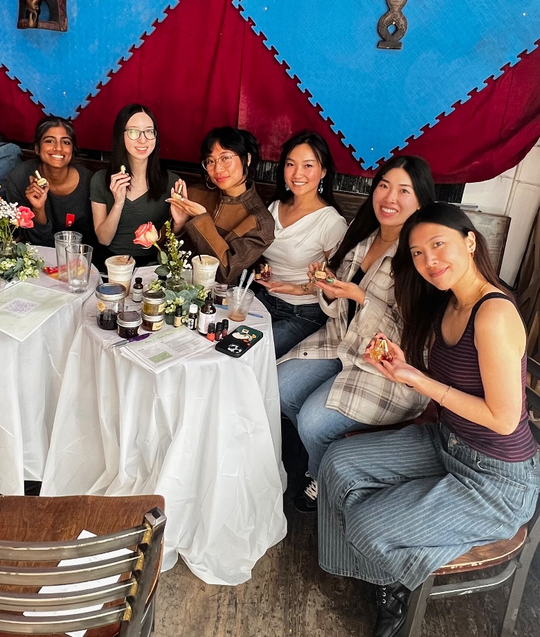 Six attendees smiling with the perfumes they made at an EVE workshop