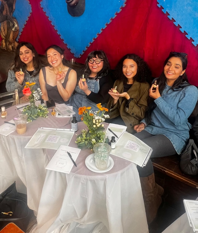 Five attendees holding up their handmade perfumes at an EVE workshop